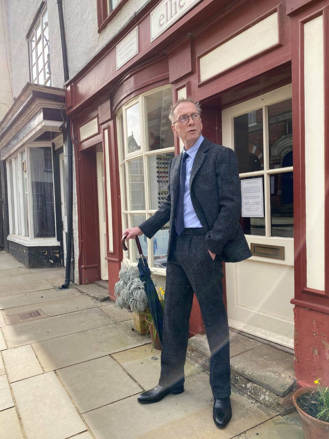 Man standing in a black suit in front of Ellie's store